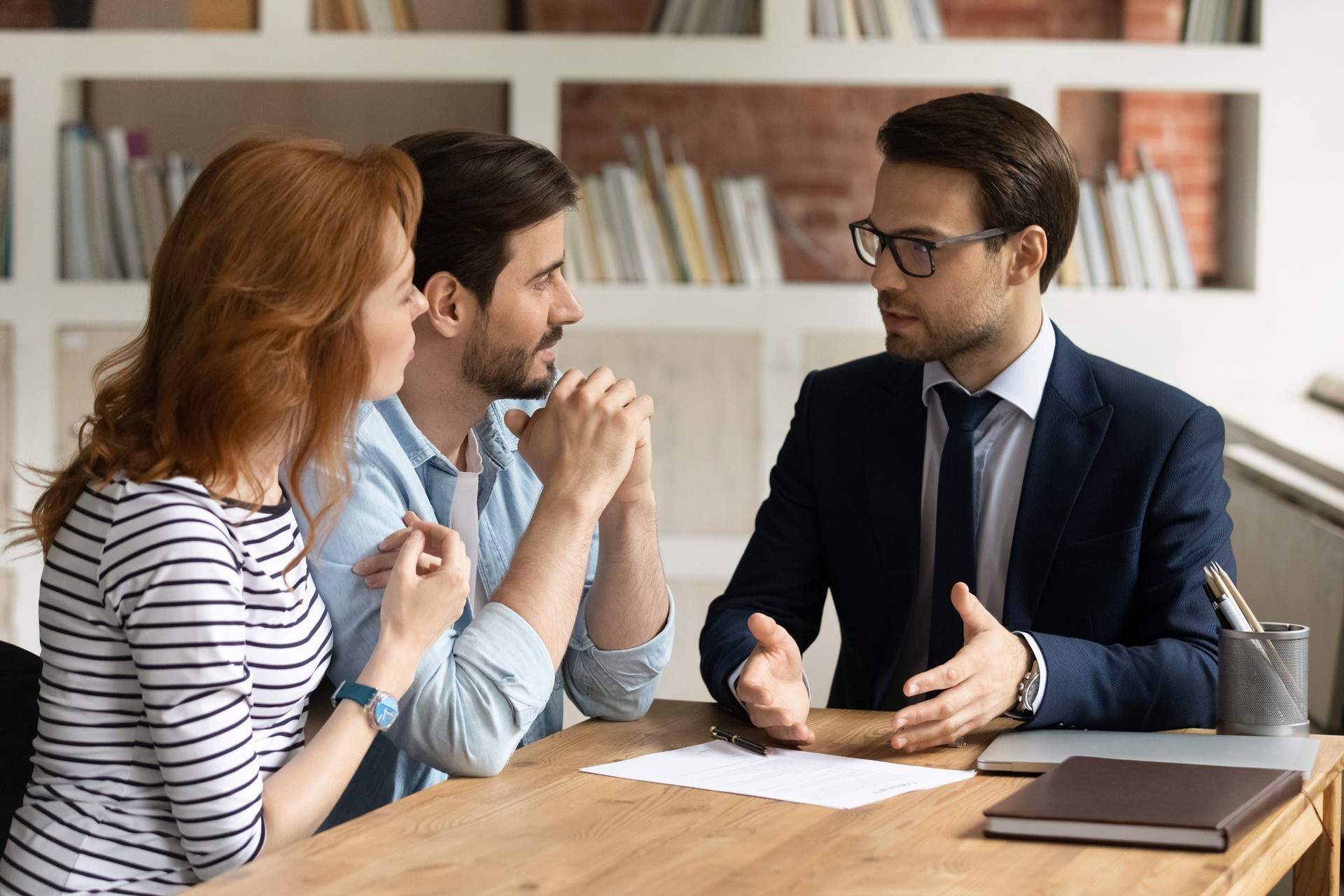 Interested young family couple visiting financial advisor in office.