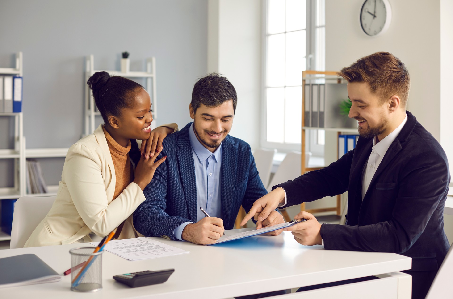 Happy mixed ethnicity couple customers sign mortgage loan contract document