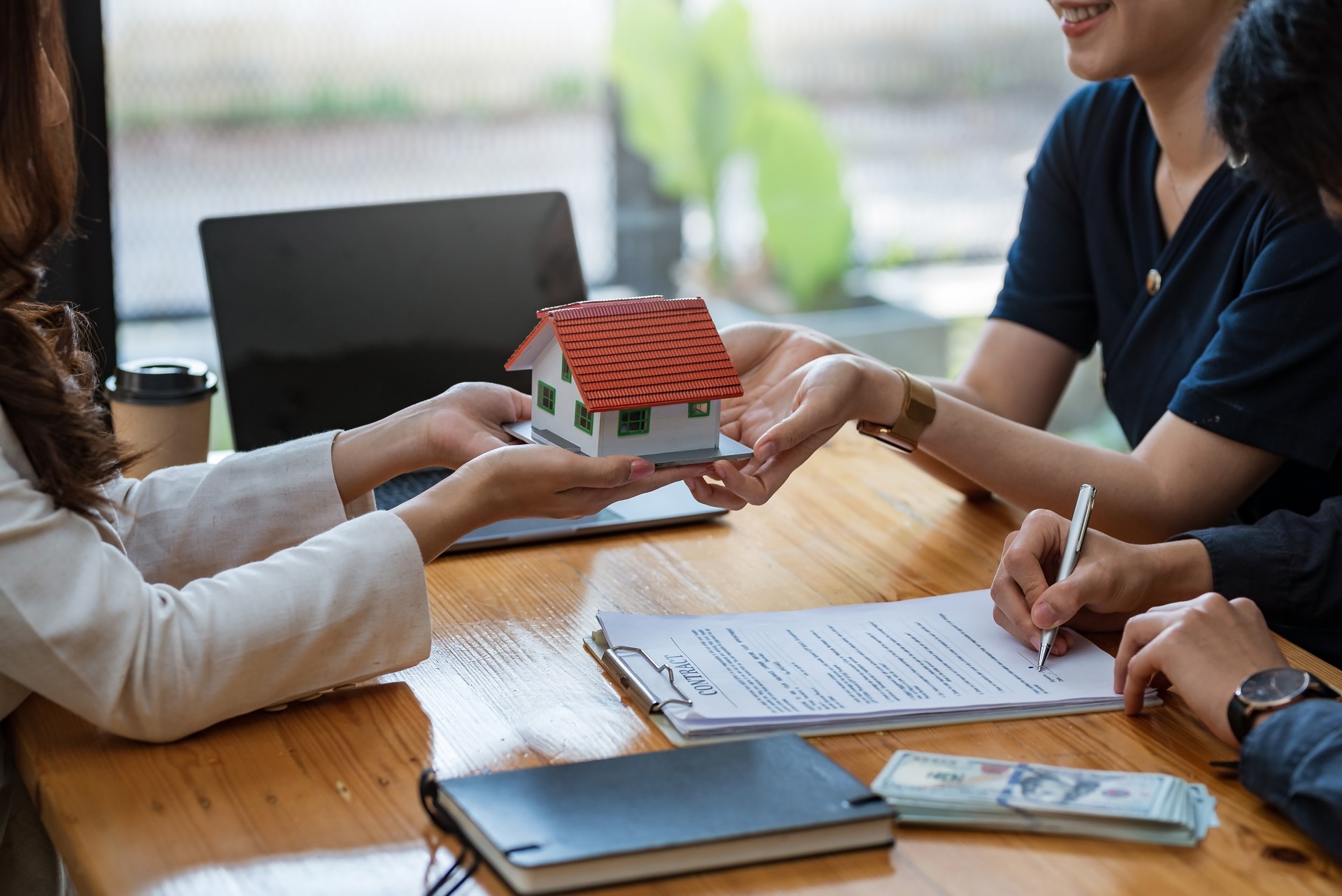 Young married couple talking to a real estate agent to sign a house purchase contract.